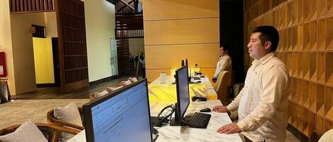 Un moderno vestíbulo de hotel con mesas de mármol, computadoras y asientos cómodos.