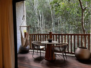 A wooden deck with a round table and four wicker chairs, surrounded by a wooden railing. - Hotel Mundo Maya Calakmul (Calakmul)