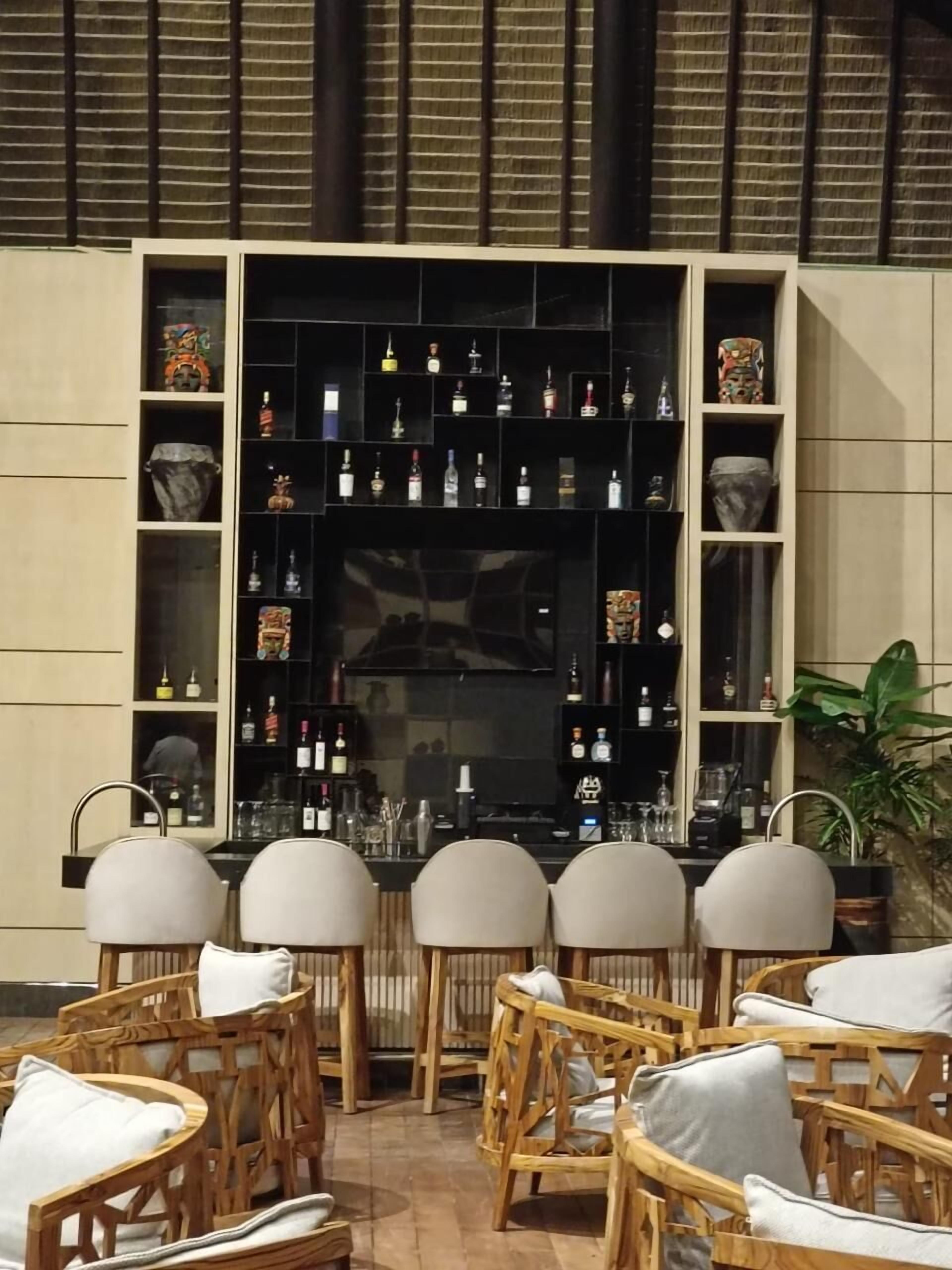 A bar area with wicker chairs and a shelf of bottles.