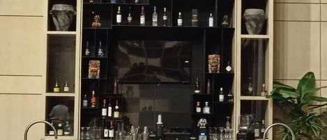 A bar area with wicker chairs and a shelf of bottles.