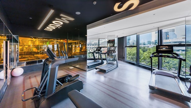 A modern gym with treadmills, ellipticals, and exercise balls, featuring large windows and a city view. - CitiGO Hotel Ouzhuang (Guangzhou)