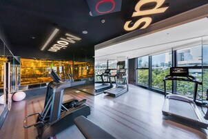 Una palestra moderna con tapis roulant, ellittiche e palle da ginnastica, con ampie finestre e vista sulla città.