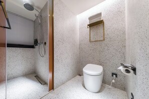 Un baño moderno con ducha, inodoro y un perchero para toallas.