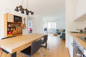 A modern kitchen with a wooden table and chairs, a built-in microwave, and a hanging light fixture.