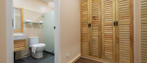 A bathroom with a toilet, sink, mirror, and wooden wardrobe.