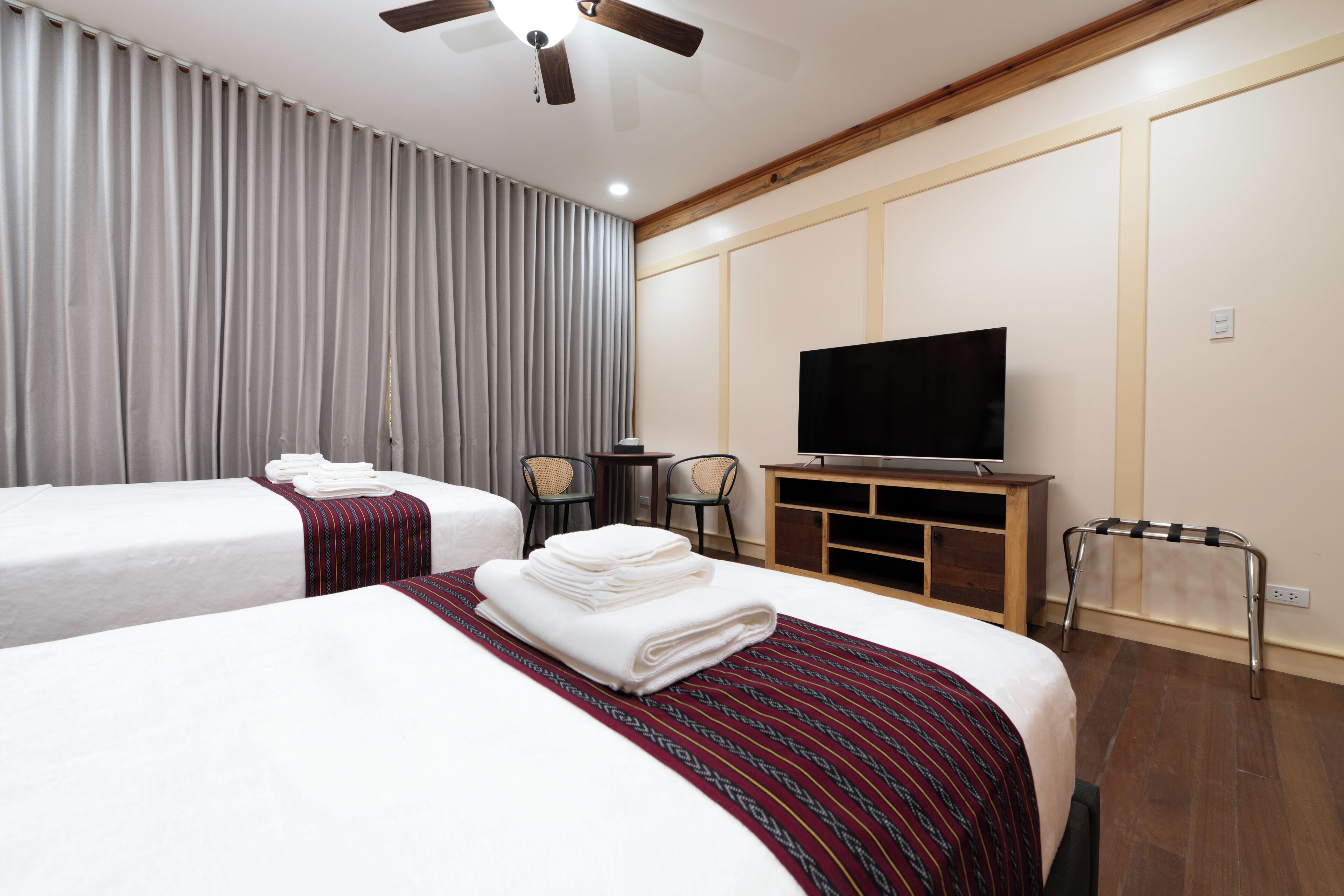 Ett hotellrum med två sängar, en TV, ett skrivbord och en takfläkt.