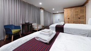 Une chambre d’hôtel avec deux lits, un bureau, une chaise et une armoire.