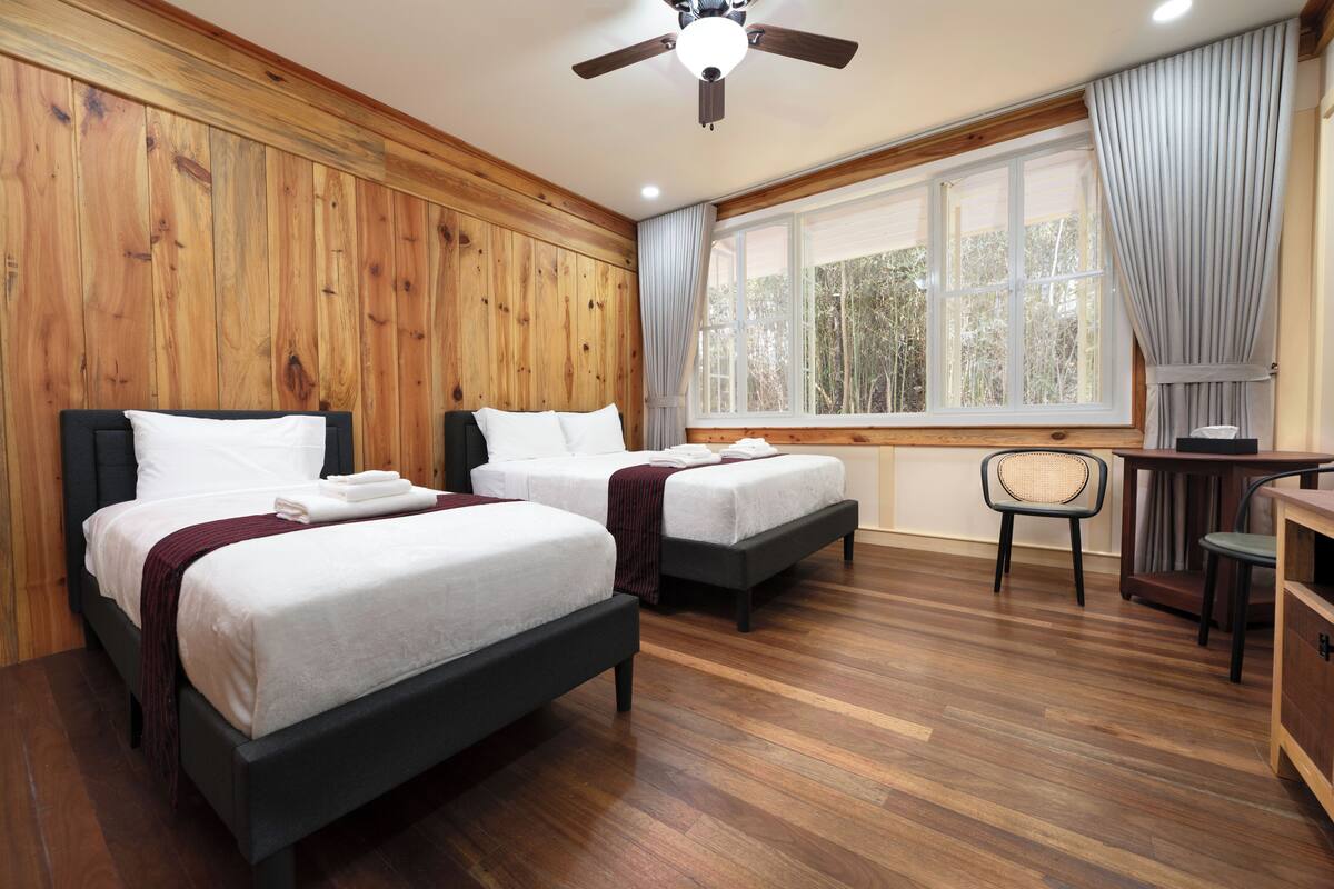 Quarto com duas camas, uma escrivaninha e uma cadeira.