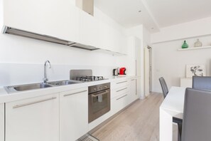 A modern kitchen with white cabinets, stainless steel appliances, and a dining area with a table and chairs.