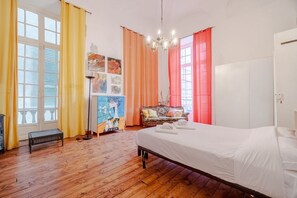 A room with a bed, a bench, a sofa, and a painting on the wall. - GuestHost - In the heart of Porto Antico, on Via San Luca, a stunning 200 sqm historic apartment in a 18th-century building. With 6-meter-high ceilings and elegant spaces, it accommodates up to 7 guests. Located in a lively pedestrian area full of histor (Genova)