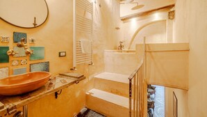 Casa de banho com uma grande pia oval, espelho, porta-toalhas e zona de duche.