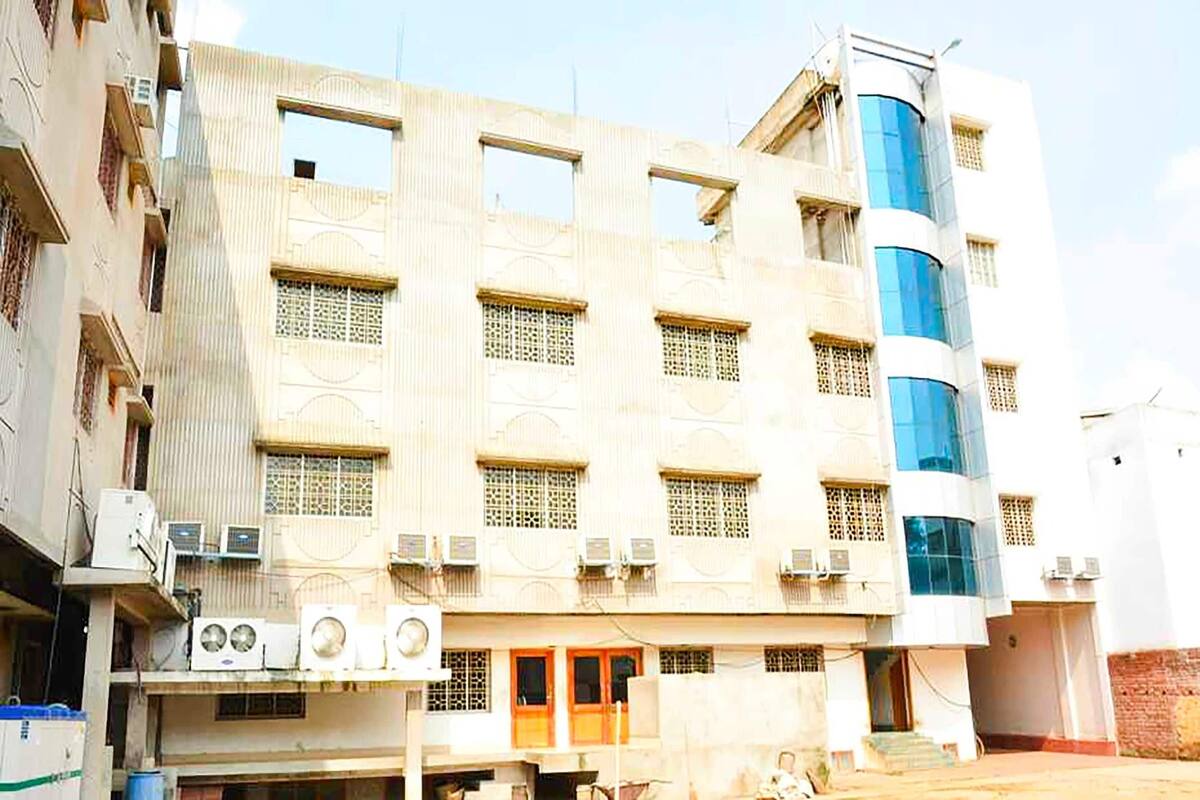 A multi-story building with a central entrance, air conditioning units, and a modern glass section.