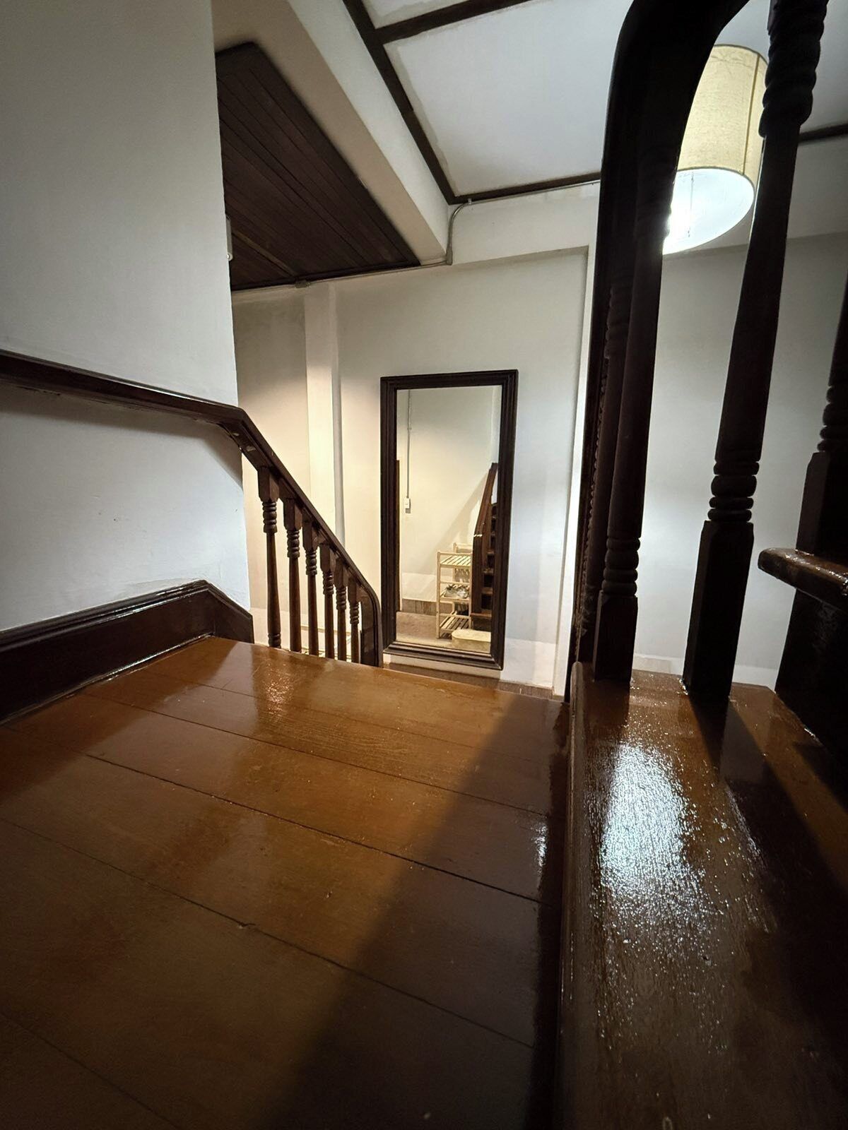 Un escalier en bois mène à une pièce où se trouvent un lit et une table de chevet.