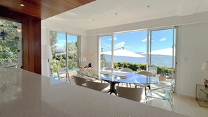 A spacious room with a large glass table and chairs, a wooden ceiling, and a view of the sea through large windows. - Bassin front villa with private beach access, heated pool - 14 pers (Andernos-les-Bains)