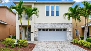 A modern two-story house with a stone facade, a garage, and palm trees. - Charming Home near Disney: Theme Rooms, Foosball & Waterpark - 370LA (Kissimmee)