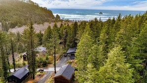 A cabin complex surrounded by dense forest, with a road leading to the main building. - Walk to Beach, Arch Cape Getaway w/ Vibrant Interior | Cape Wonder by AvantStay (Arch Cape)