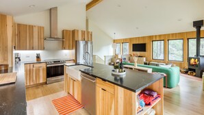 A modern kitchen with wooden cabinets, stainless steel appliances, and a large island. - Walk to Beach, Arch Cape Getaway w/ Vibrant Interior | Cape Wonder by AvantStay (Arch Cape)