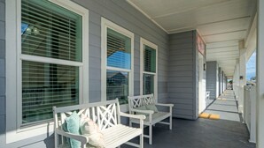 A covered porch with two white benches and large windows.