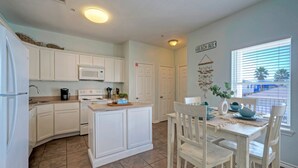 A kitchen with white cabinets, a microwave, a stove, and a dining area with a table and chairs.