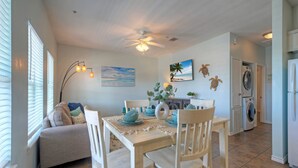 A dining area with a table set for four, a ceiling fan, and a wall-mounted washing machine.