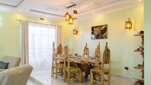 A dining area with a round table, wooden chairs, and pendant lighting.