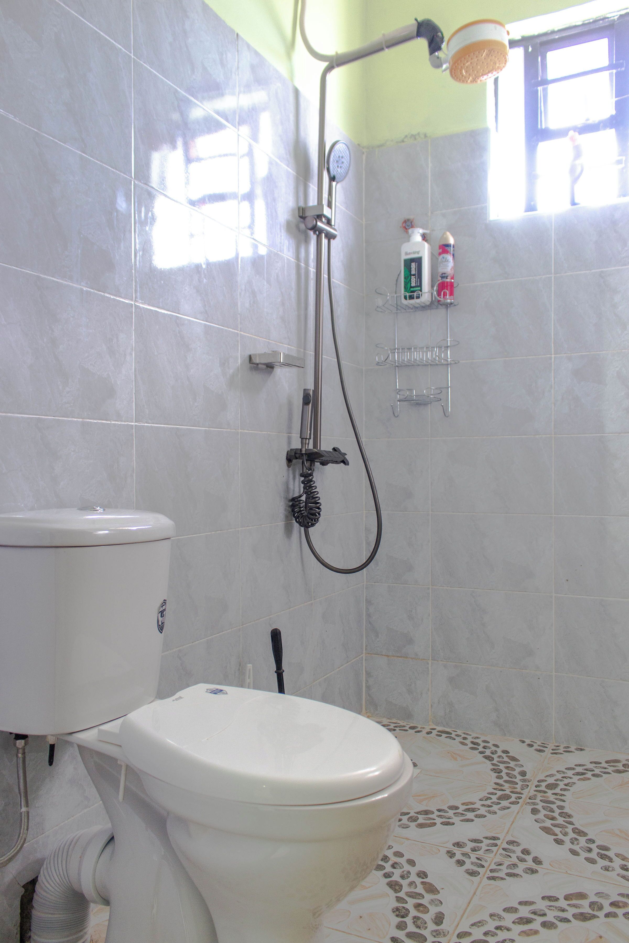 A bathroom with a toilet, shower, and tiled floor.