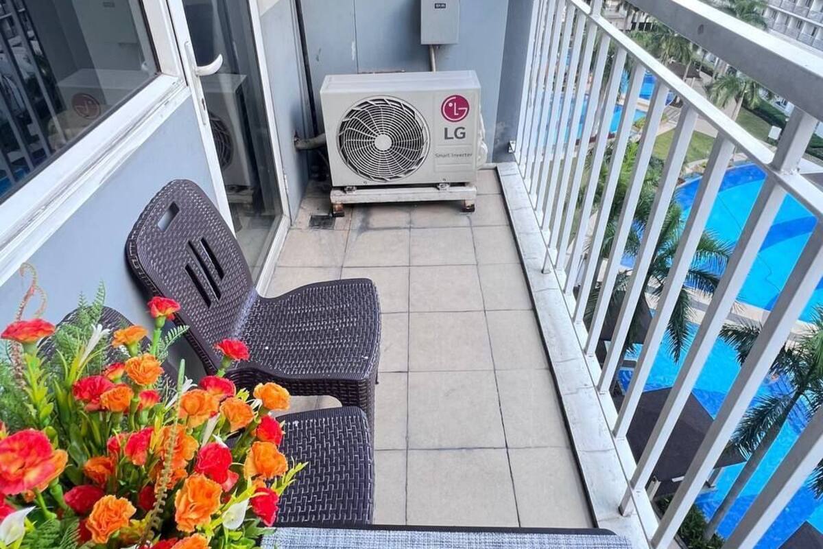 Ein Balkon mit Sitzgelegenheit, Klimaanlage und Blick auf einen Swimmingpool.