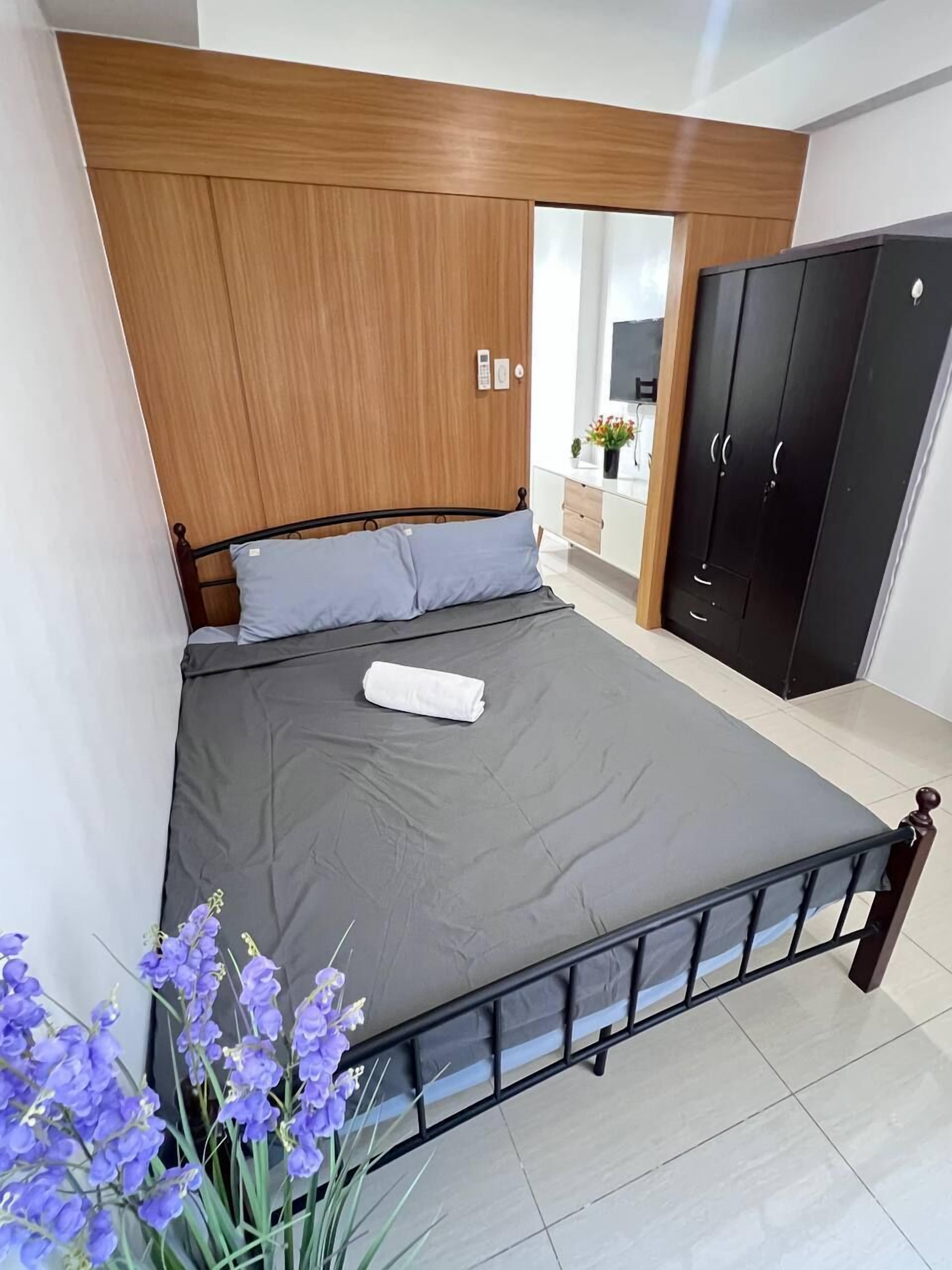 A bedroom with a bed, a wooden headboard, a wardrobe, and a bathroom visible in the background.