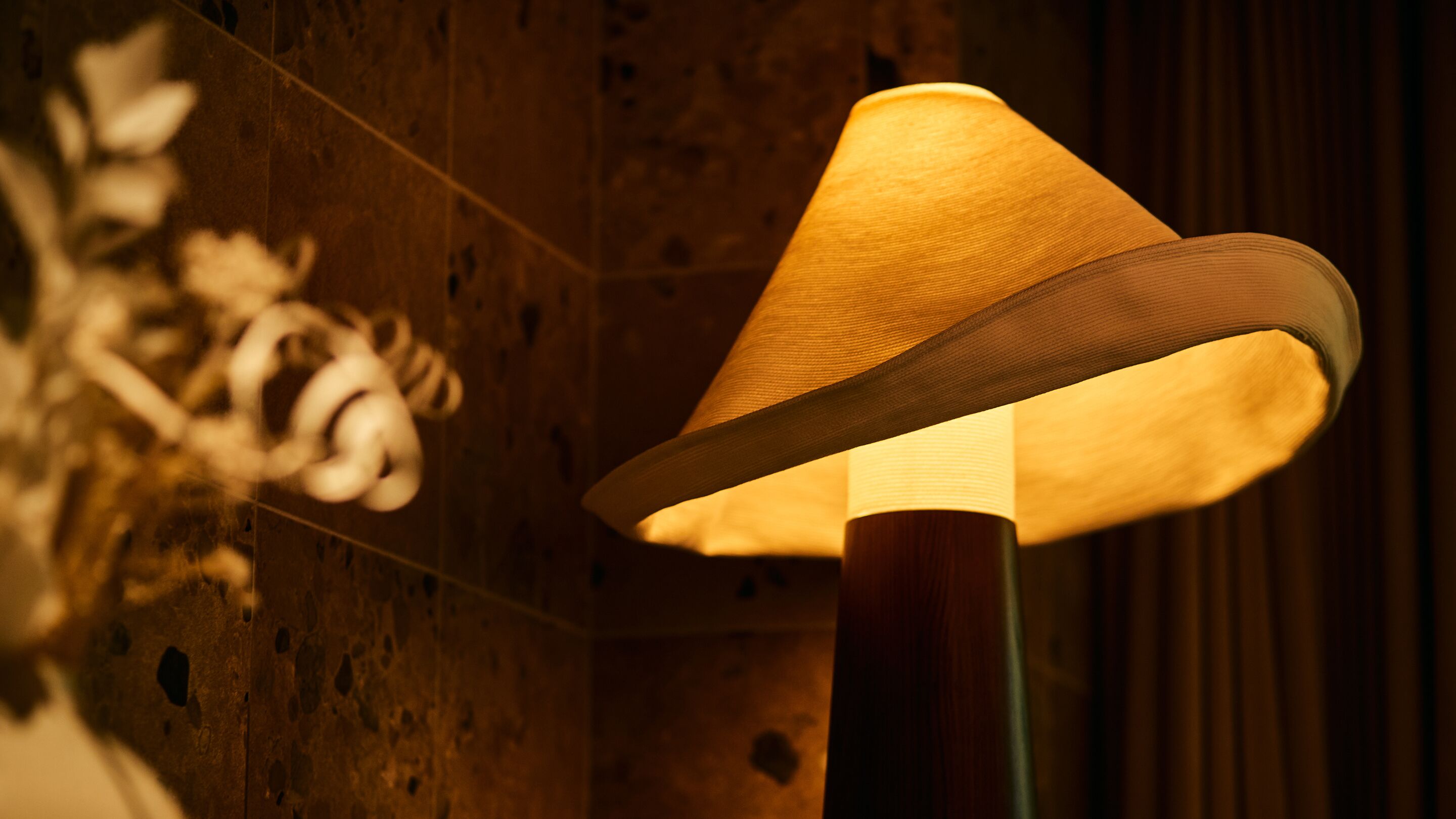 A lamp with a conical shade in a room with wooden walls.
