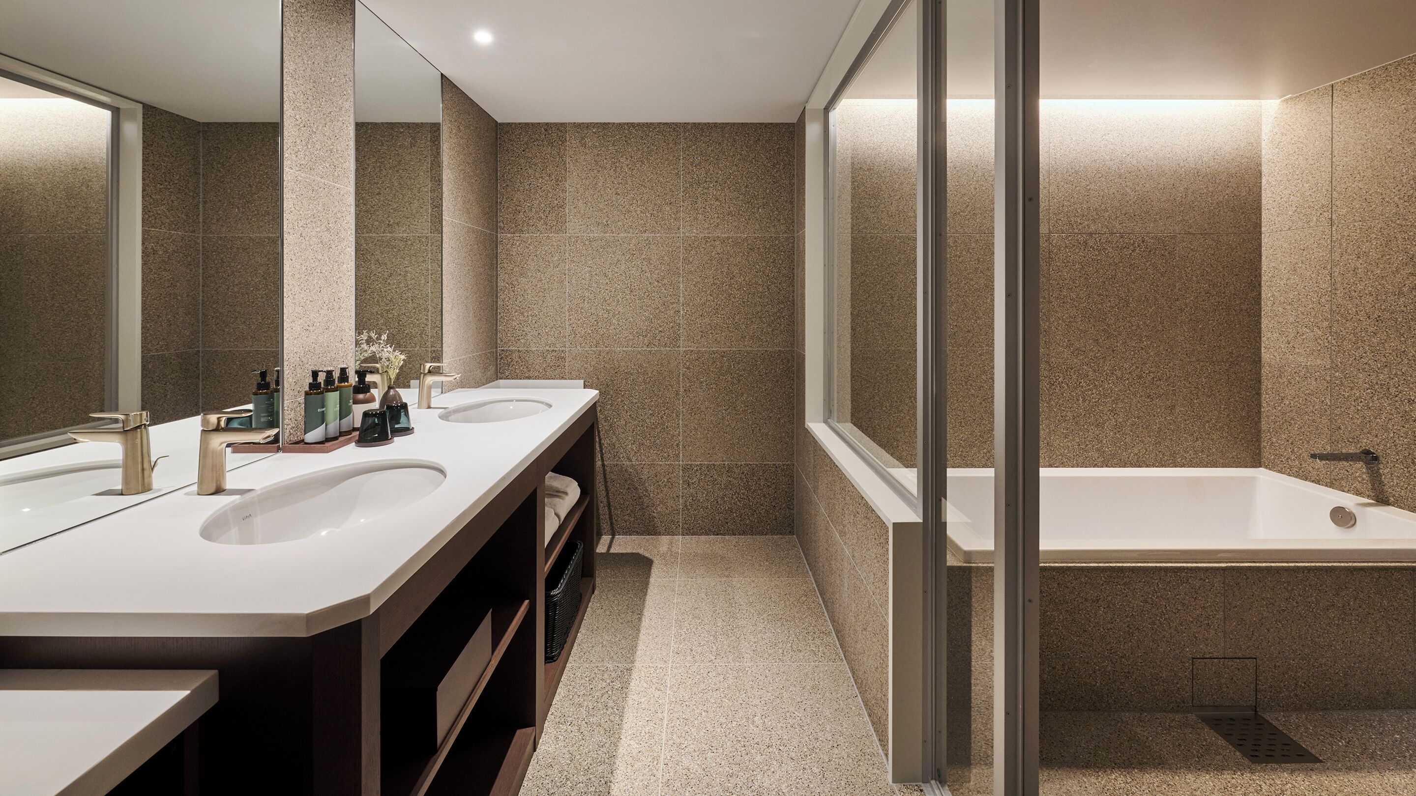 A modern bathroom with two sinks, a large mirror, and a bathtub.