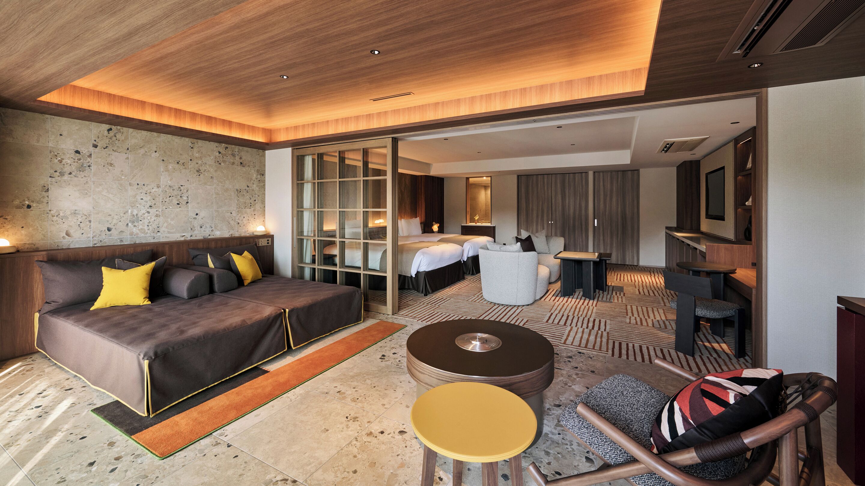 Une chambre d’hôtel moderne avec un grand lit, un canapé, une petite table ronde et un coin salon avec un fauteuil.