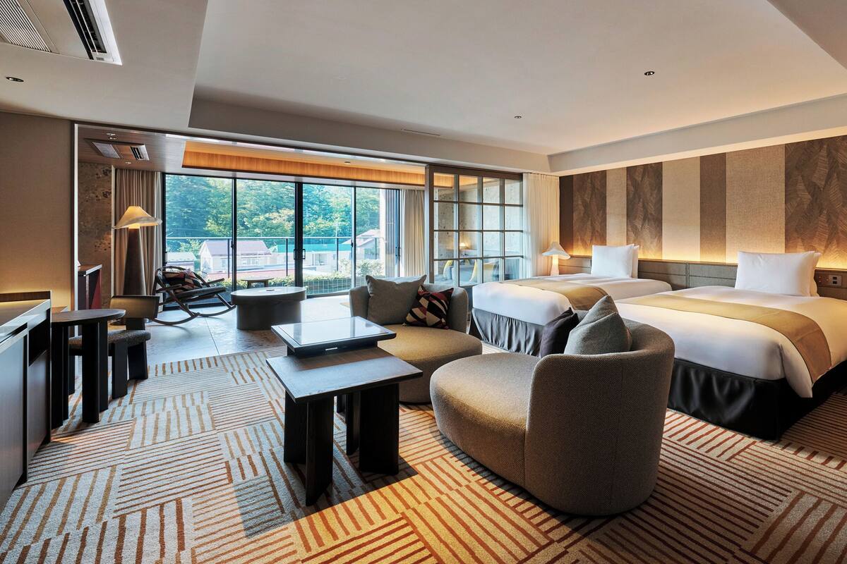 Ein Hotelzimmer mit einem großen Bett, einem Sofa, einem Schreibtisch und Blick ins Freie.