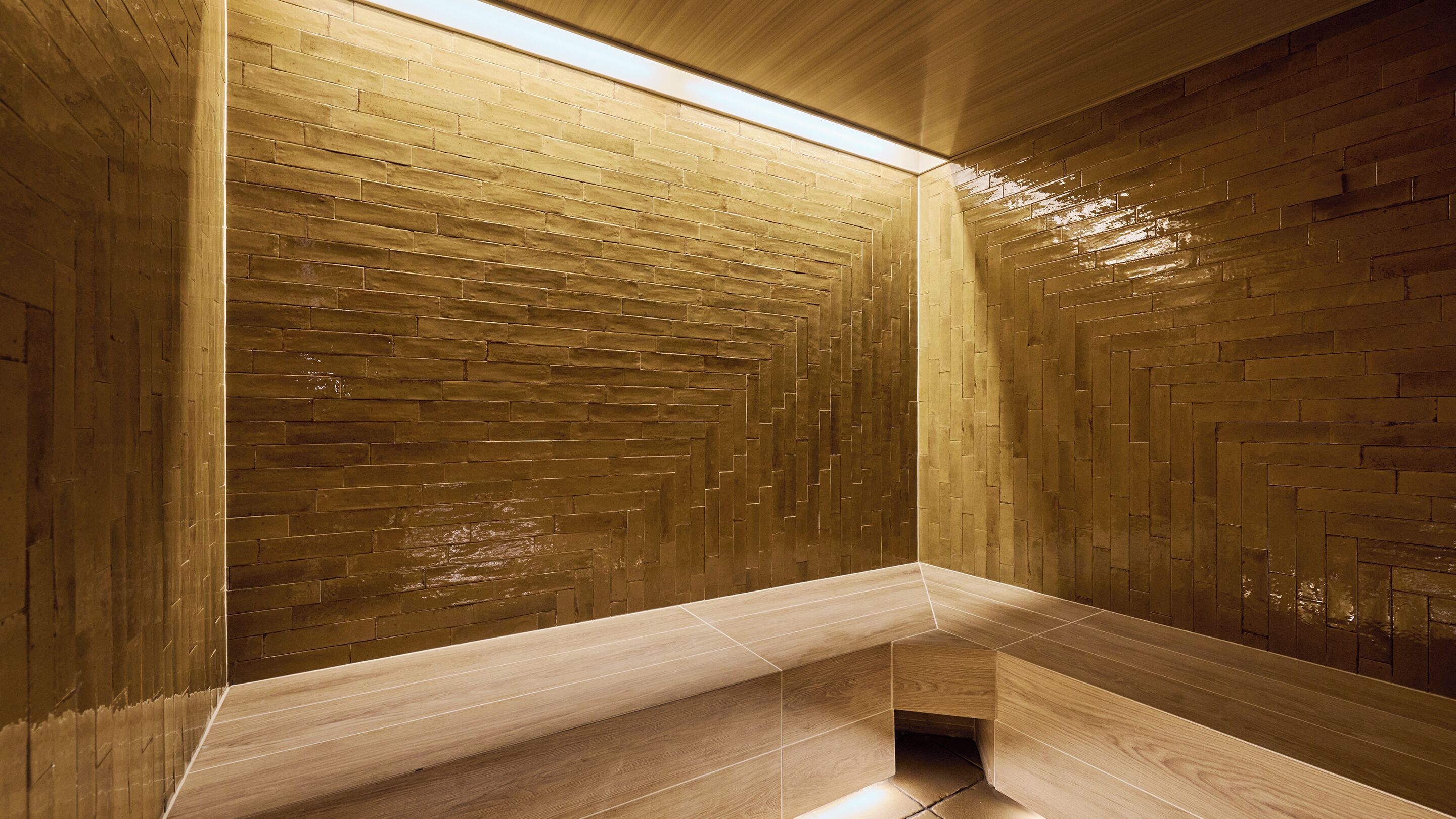 A modern bathroom with a wooden herringbone pattern wall and a bench.