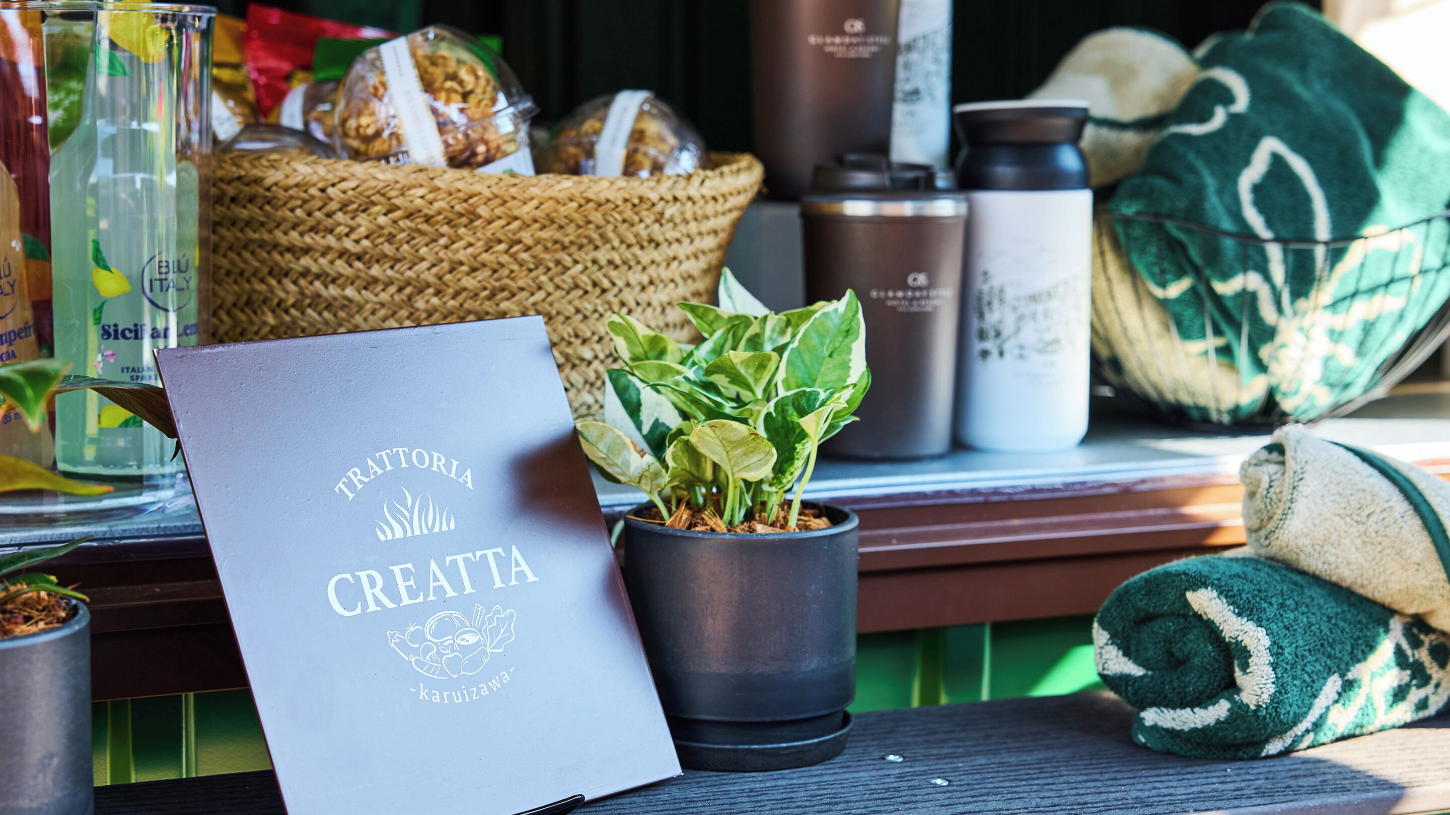 A tray table with a menu, a potted plant, and various items on a table.
