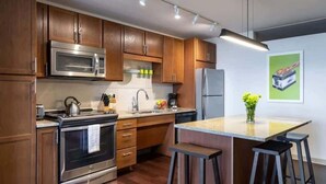 Una cocina moderna con armarios de madera, electrodomésticos de acero inoxidable y una isla central con taburetes de bar.