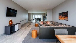 Una sala de estar moderna con un sofá, una mesa de centro, un televisor y un cuadro en la pared.