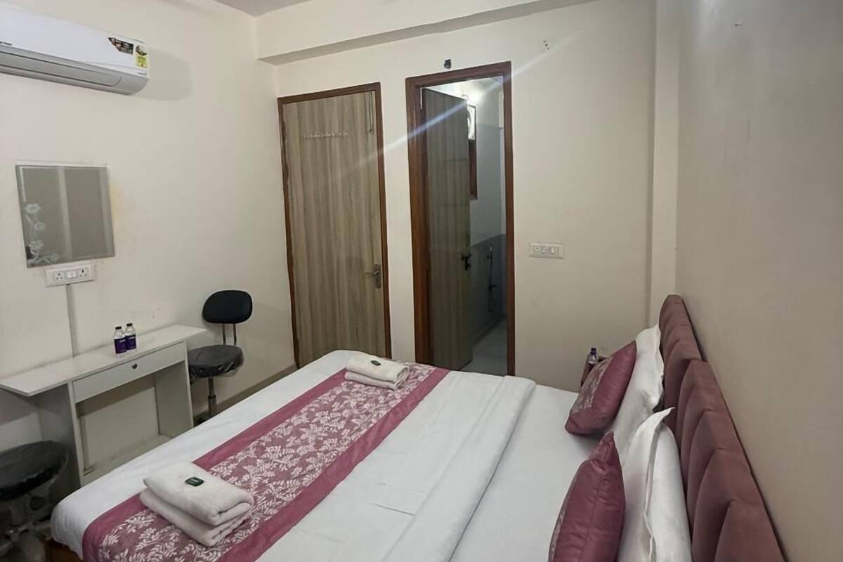 Una habitación de hotel con cama, escritorio, silla, ventilador de techo y espejo.