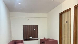Un salón de conferencias con una mesa grande, dos sofás, un biombo y un ventilador de techo, además de un panel de pared de madera.