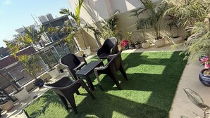 Una terraza en la azotea con césped artificial, mobiliario exterior y plantas en macetas.