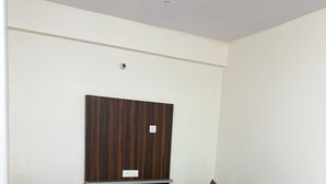 Una sala de estar con dos sofás, una mesa de centro de cristal y un televisor montado en la pared.