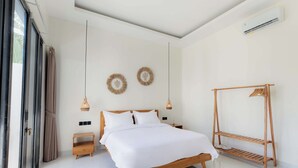 A modern bedroom with a wooden bed, a wooden bedside table, a hanging light fixture, and a wooden shelf unit. - Villa Sardegna Ubud (Ubud)