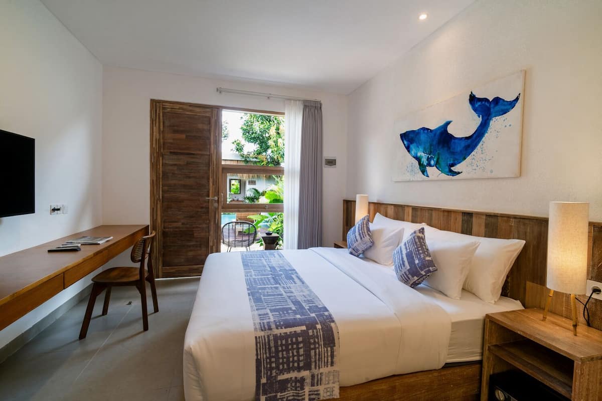 Ein Hotelzimmer mit Bett, Schreibtisch, Fernseher und einem Walgemälde.