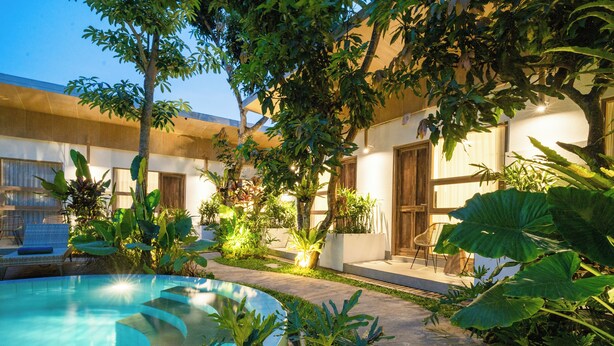 A pool area with a curved edge, surrounded by lush greenery and potted plants. - Lakubumi Pavilion (Ungasan)