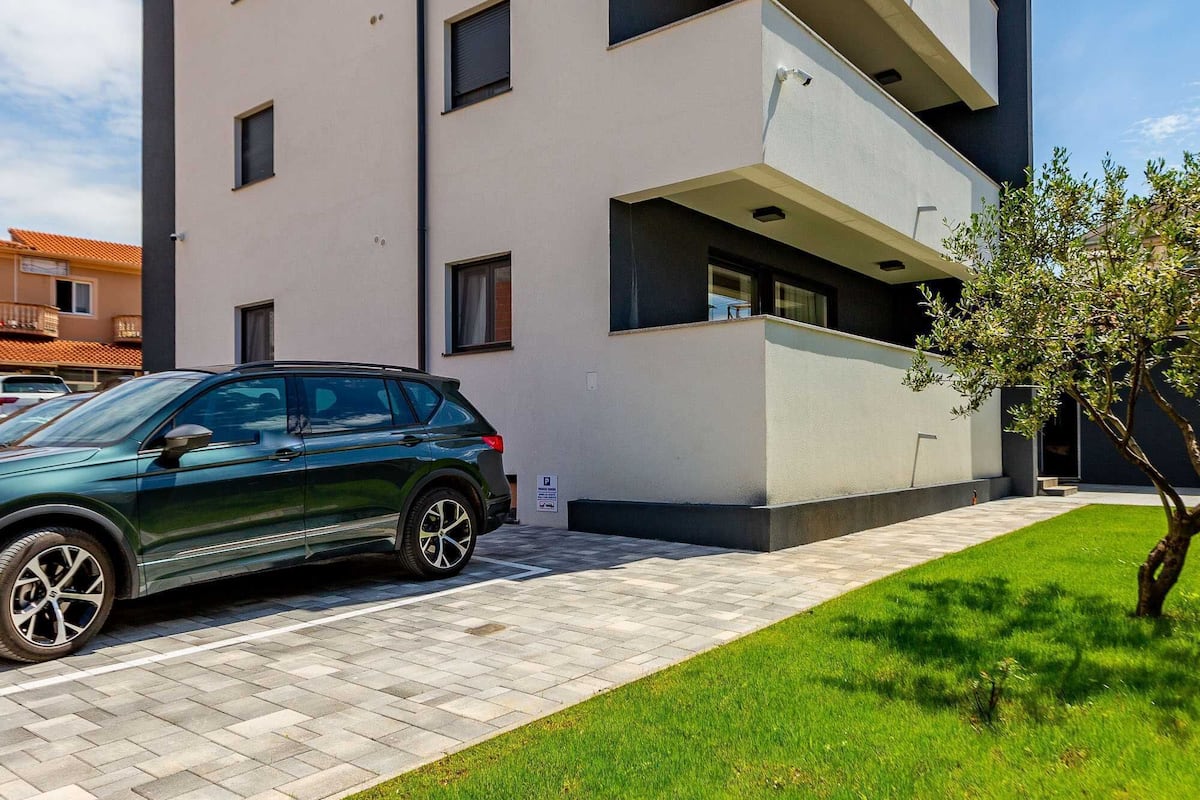 A modern multi-story building with a green car parked in front.