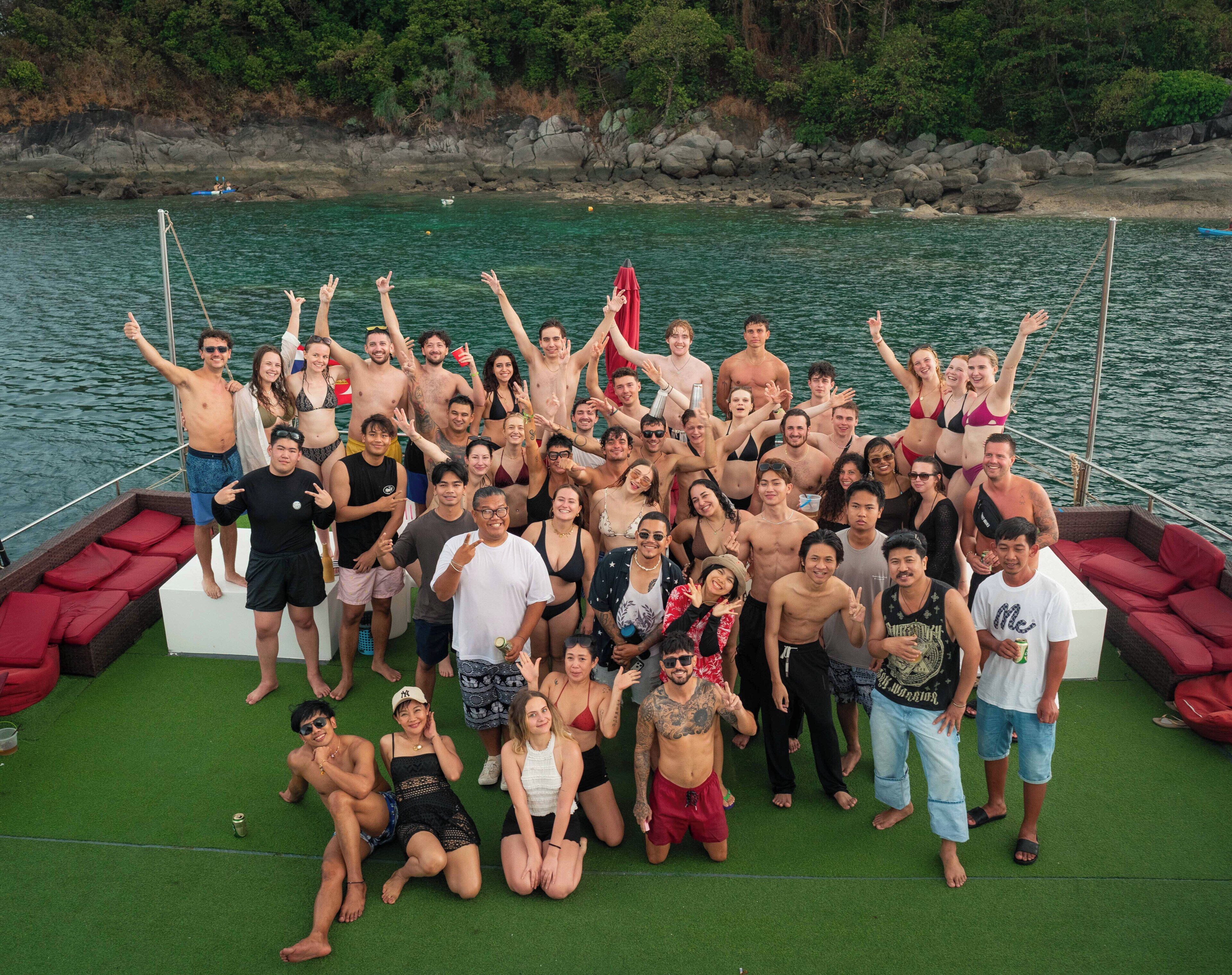 A group of people on a boat with a rocky shoreline in the background.
