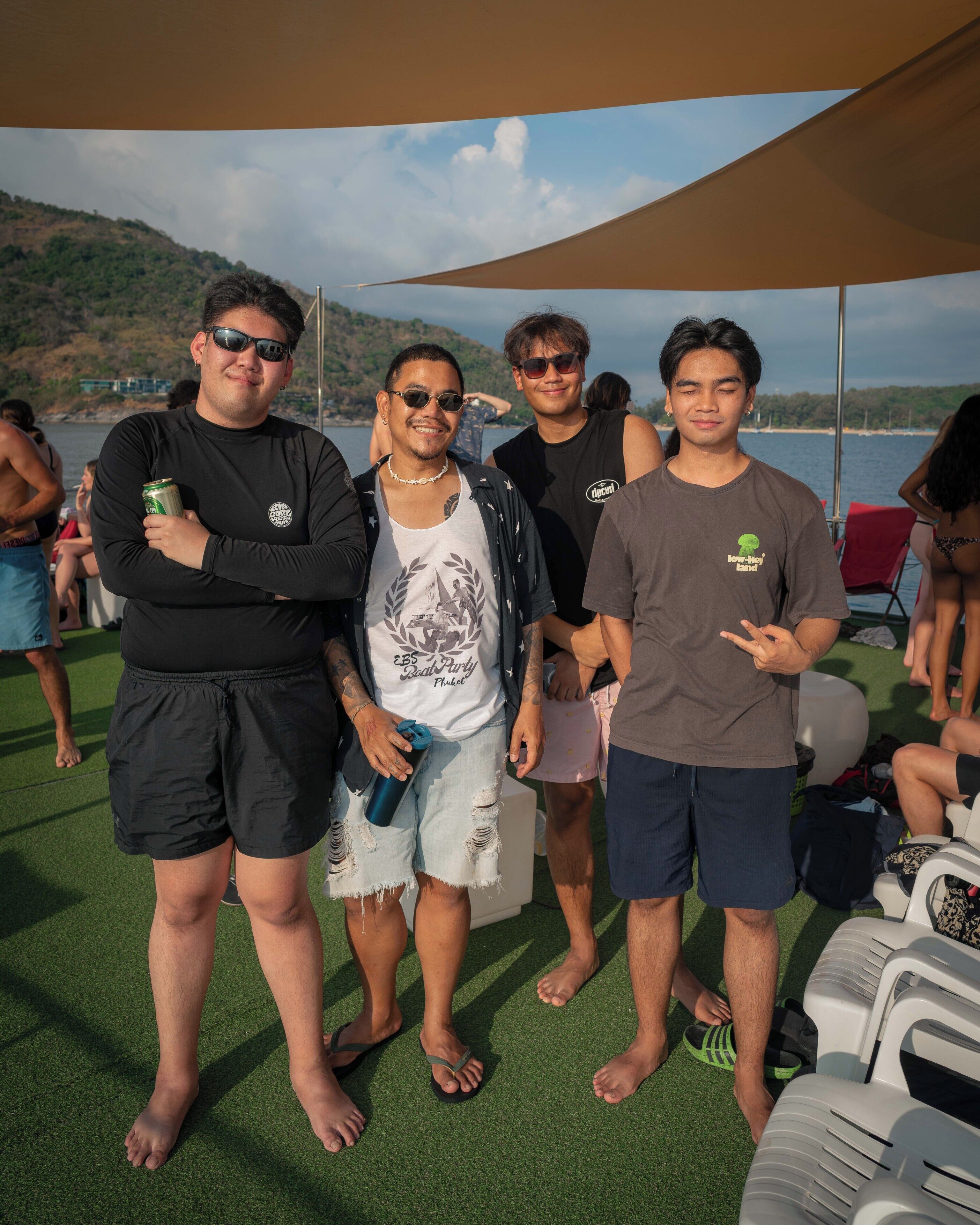 A group of people standing on a deck with a view of the water and hills in the background.