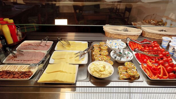 Un buffet proposant une variété de plats, notamment des viandes et des fromages en tranches, ainsi que des légumes.