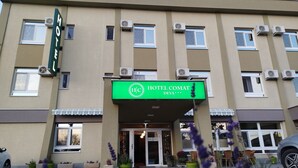 Un hôtel avec une enseigne verte sur laquelle on peut lire « HÔTEL COMAT DEVA ».
