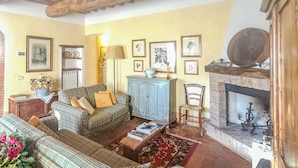 A cozy living room with a fireplace, plaid furniture, and framed pictures on the wall. - Francigena Loggia Apartment Shared Pool (Gambassi Terme)