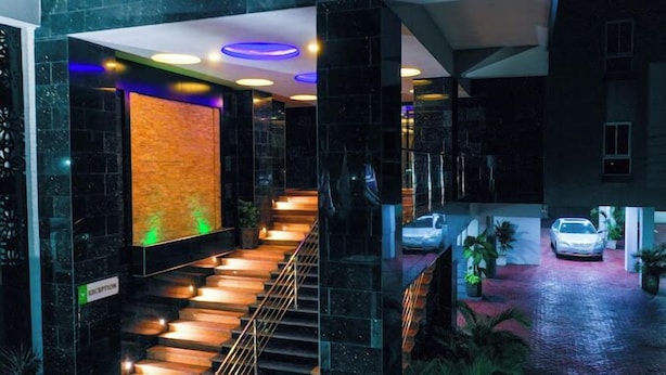 A modern hotel lobby with a staircase, a reception desk, and a car parked outside. - The Limewood Hotel (Port Harcourt)